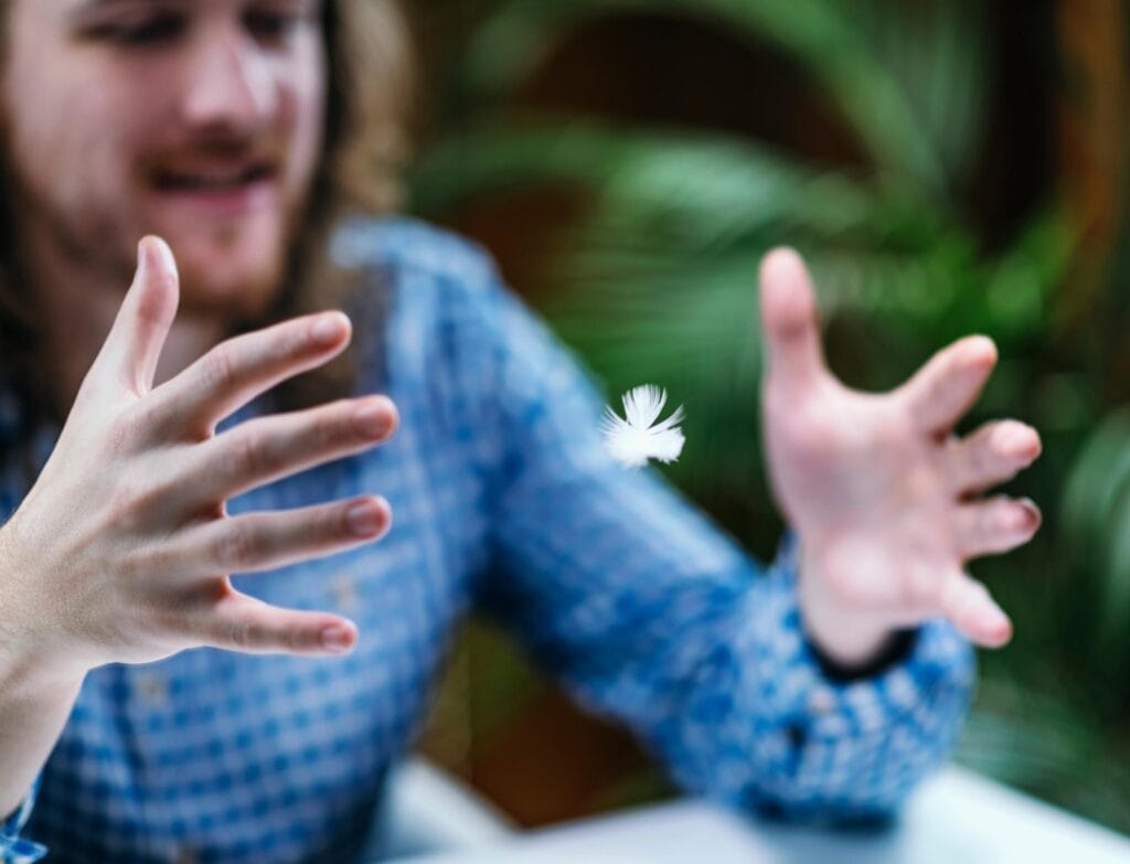 Young man practices beginner level telekinesis by levitation of a feather